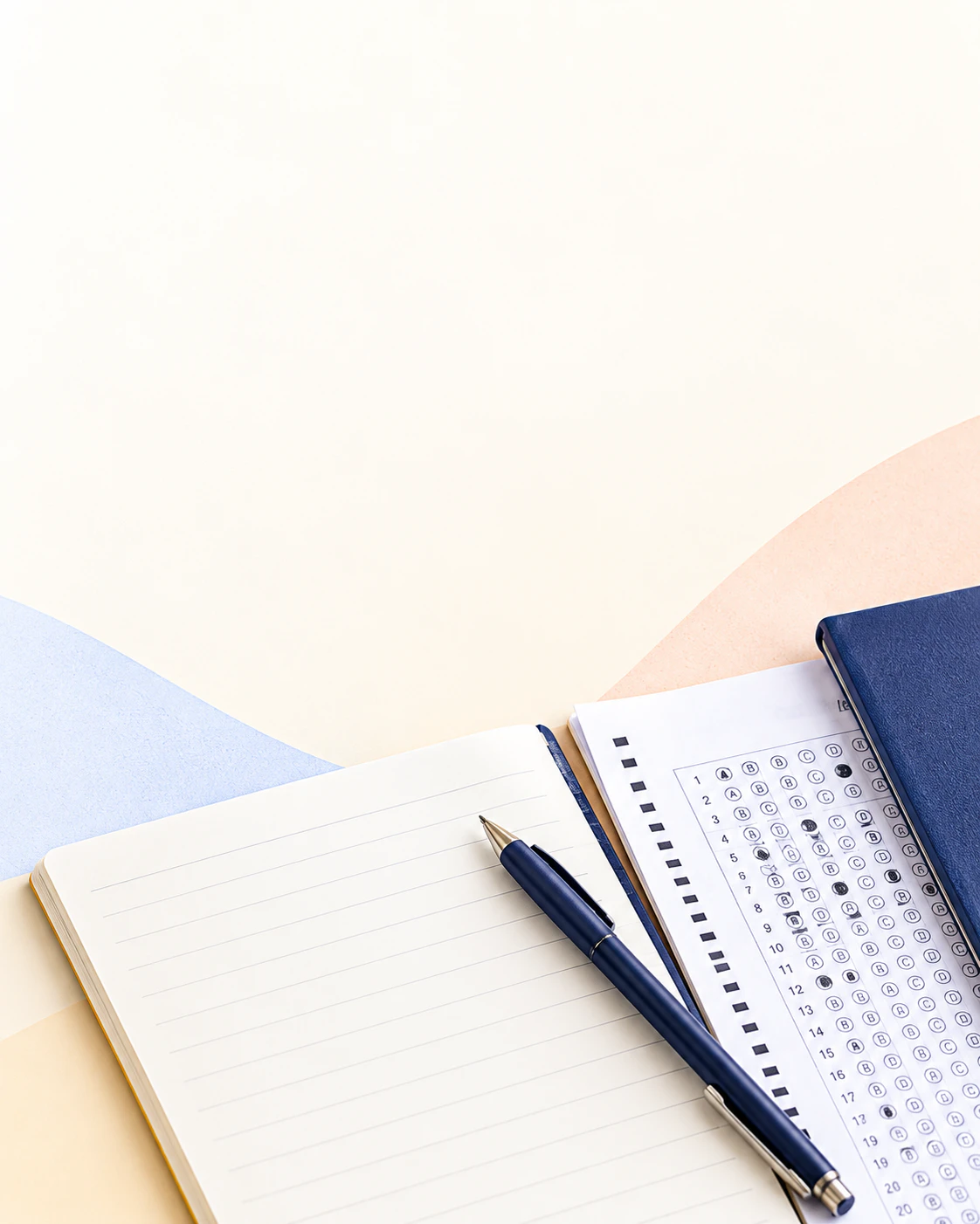 A notebook, answer sheet and pen arranged on a study desk
